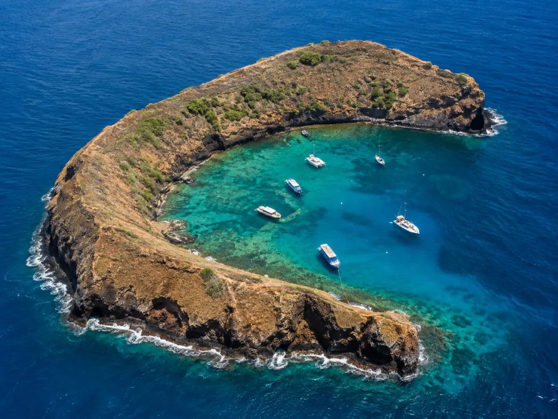 Der sichelförmige Rand von Molokini von oben, mit Booten in der geschützten inneren Bucht vertäut